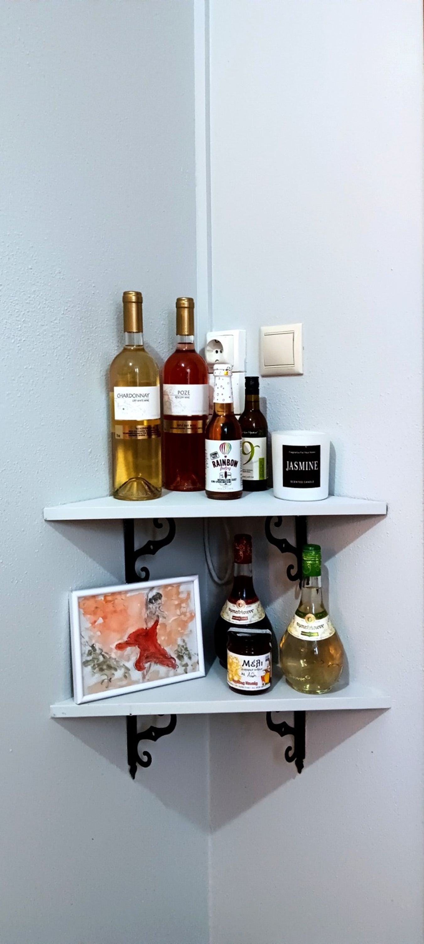 A wall-mounted shelf with various bottles and a framed picture.