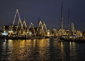 A marina at night with boats docked and illuminated by string lights. - Seaside Gem in Scheveningen (The Hague)