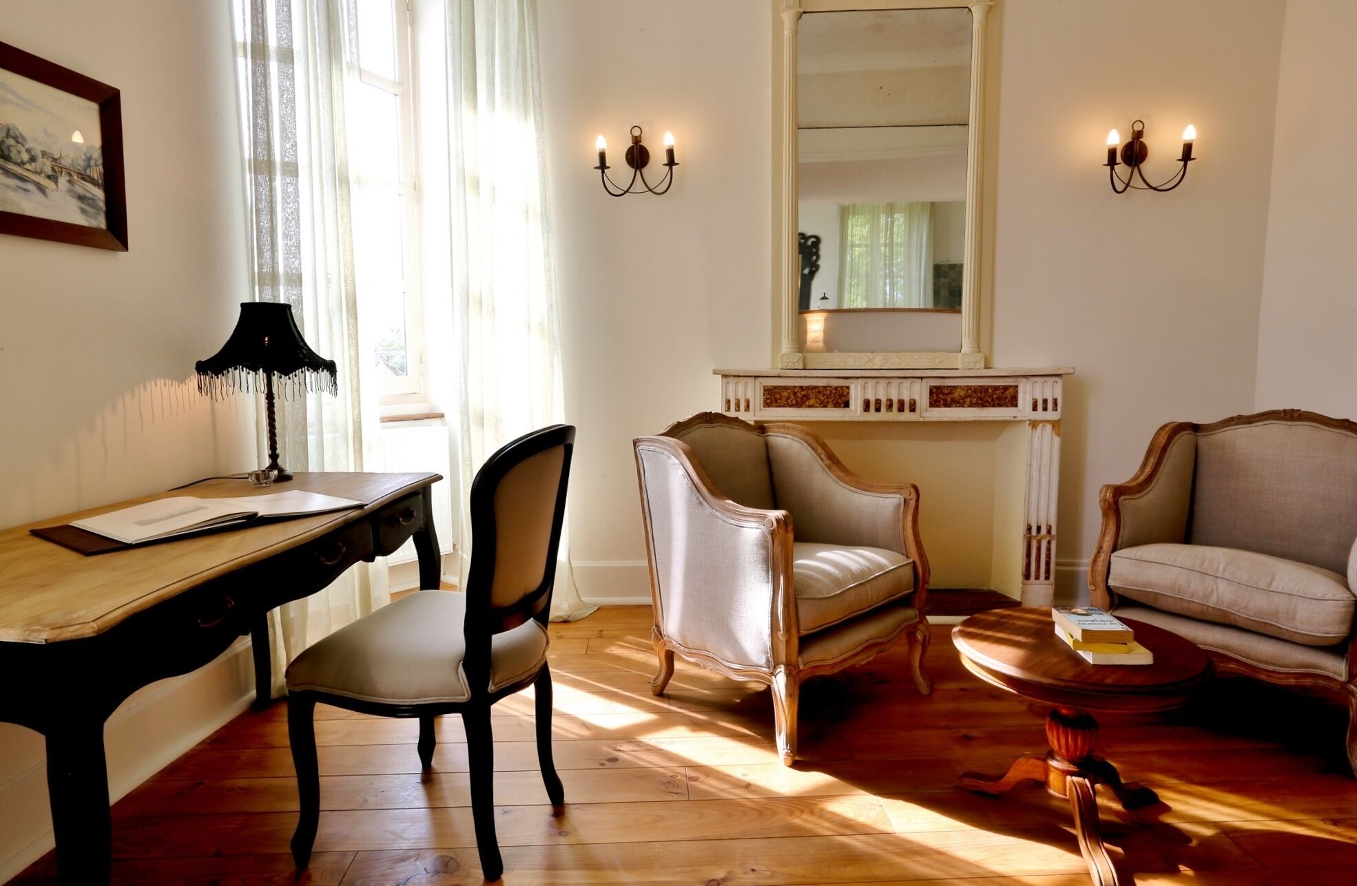 Una habitación con un escritorio de madera, dos sillas, una mesa redonda de centro y una chimenea.