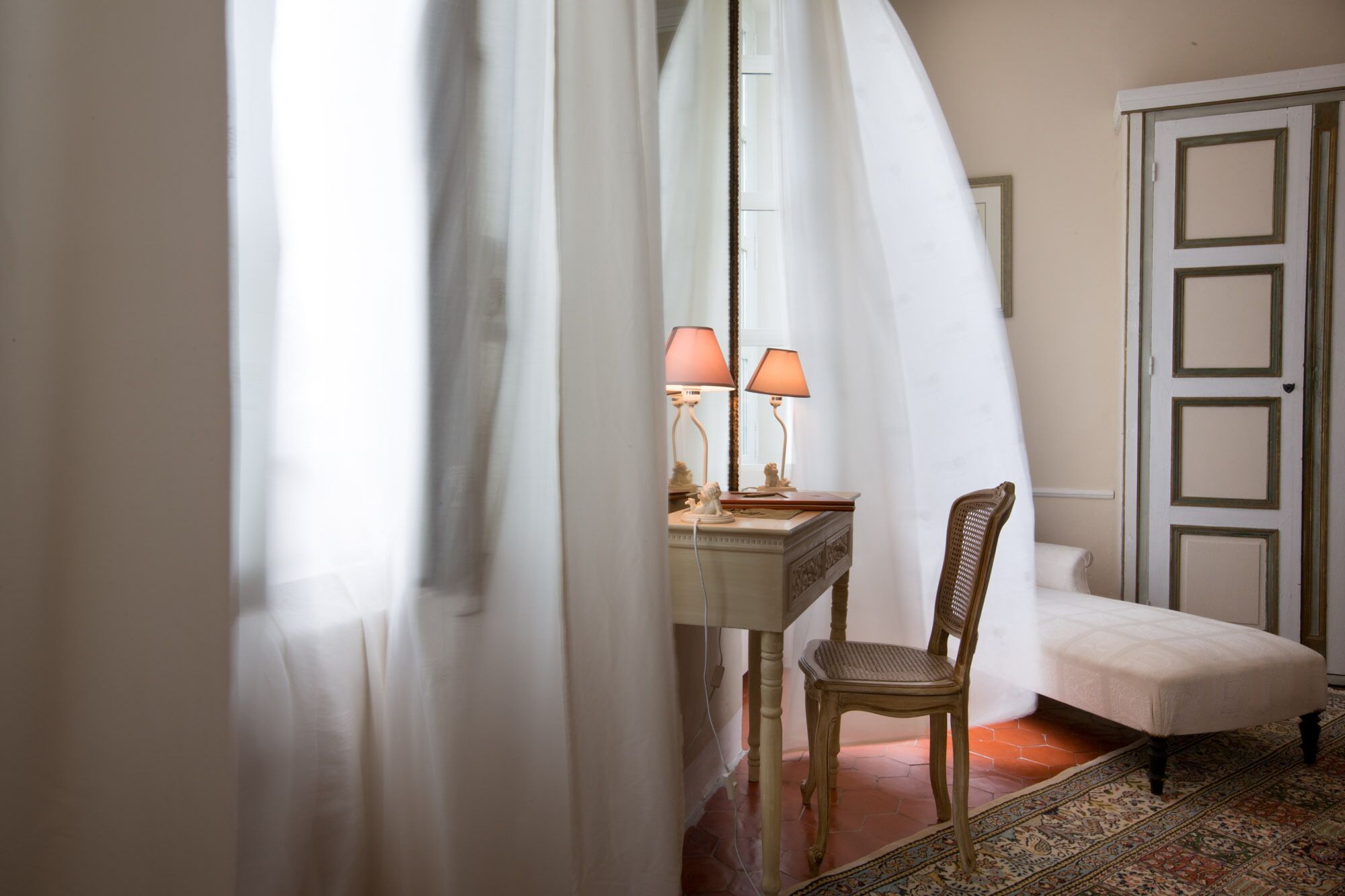 Una habitación con un escritorio, dos lámparas, una silla y un banco.