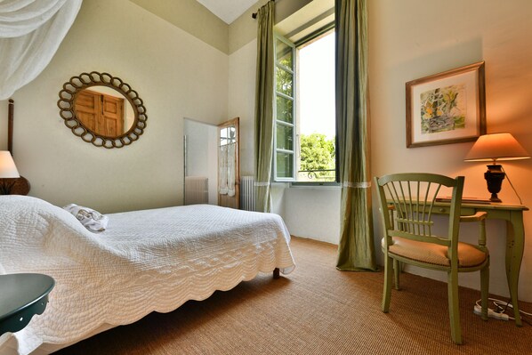 A bedroom with a bed, a chair, a table, a window with curtains, a mirror, and a painting on the wall. - Château de Potelières (Potelières)