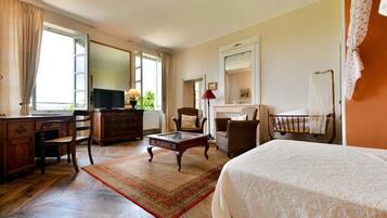 Une chambre d’hôtel équipée d’un lit, d’un bureau, d’une télévision, d’une chaise, d’une cheminée et d’une fenêtre avec des rideaux.