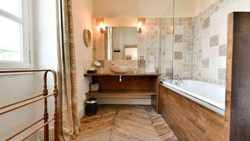 A bathroom with a wooden vanity, a large sink, a bathtub, and a herringbone-patterned floor.