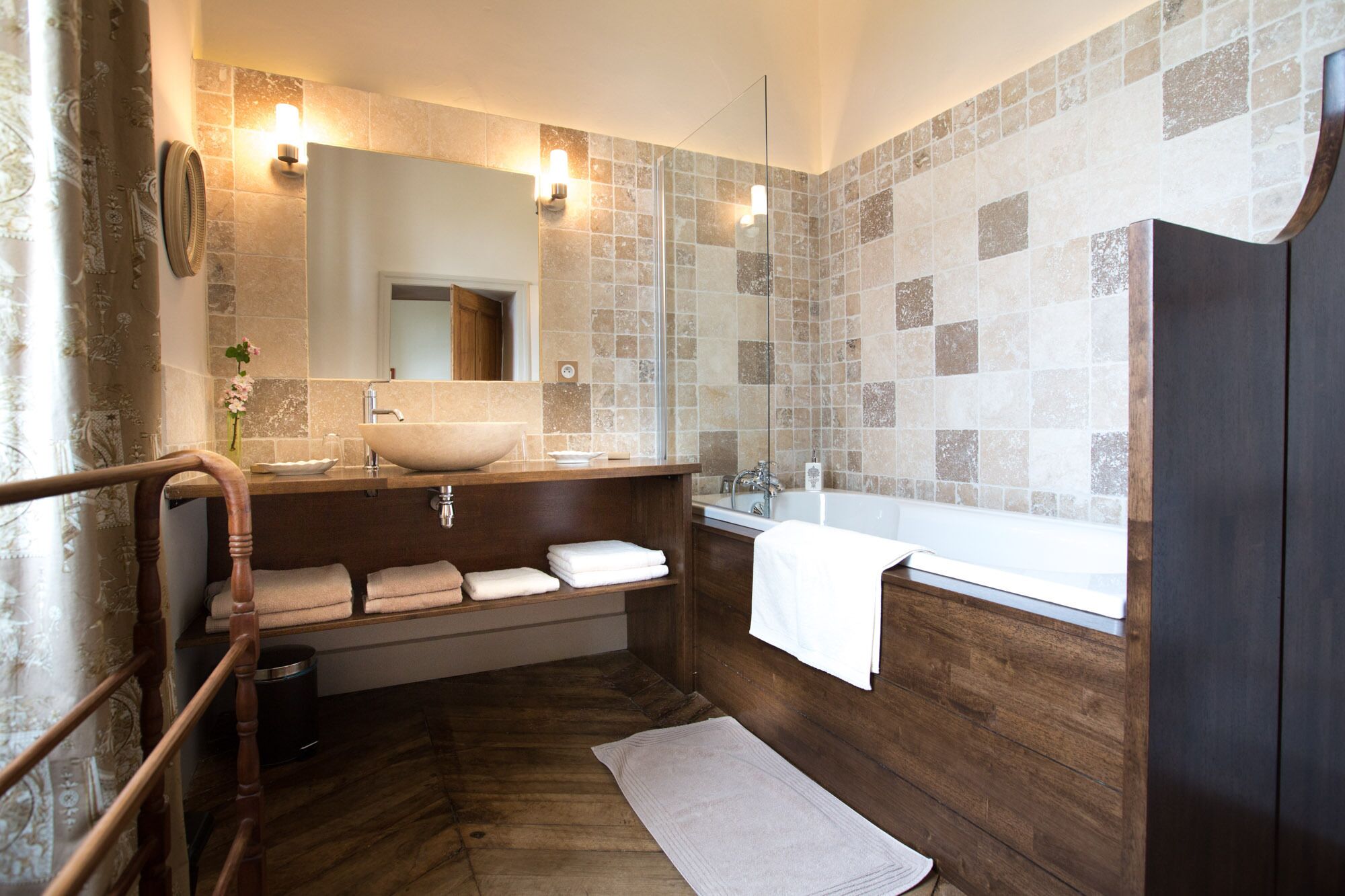 A modern bathroom with a wooden vanity, a large sink, a bathtub, and a mirror.