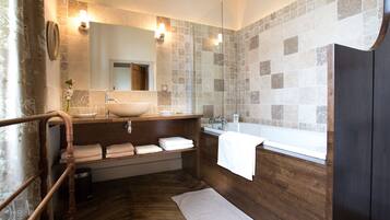A modern bathroom with a wooden vanity, a large sink, a bathtub, and a mirror.