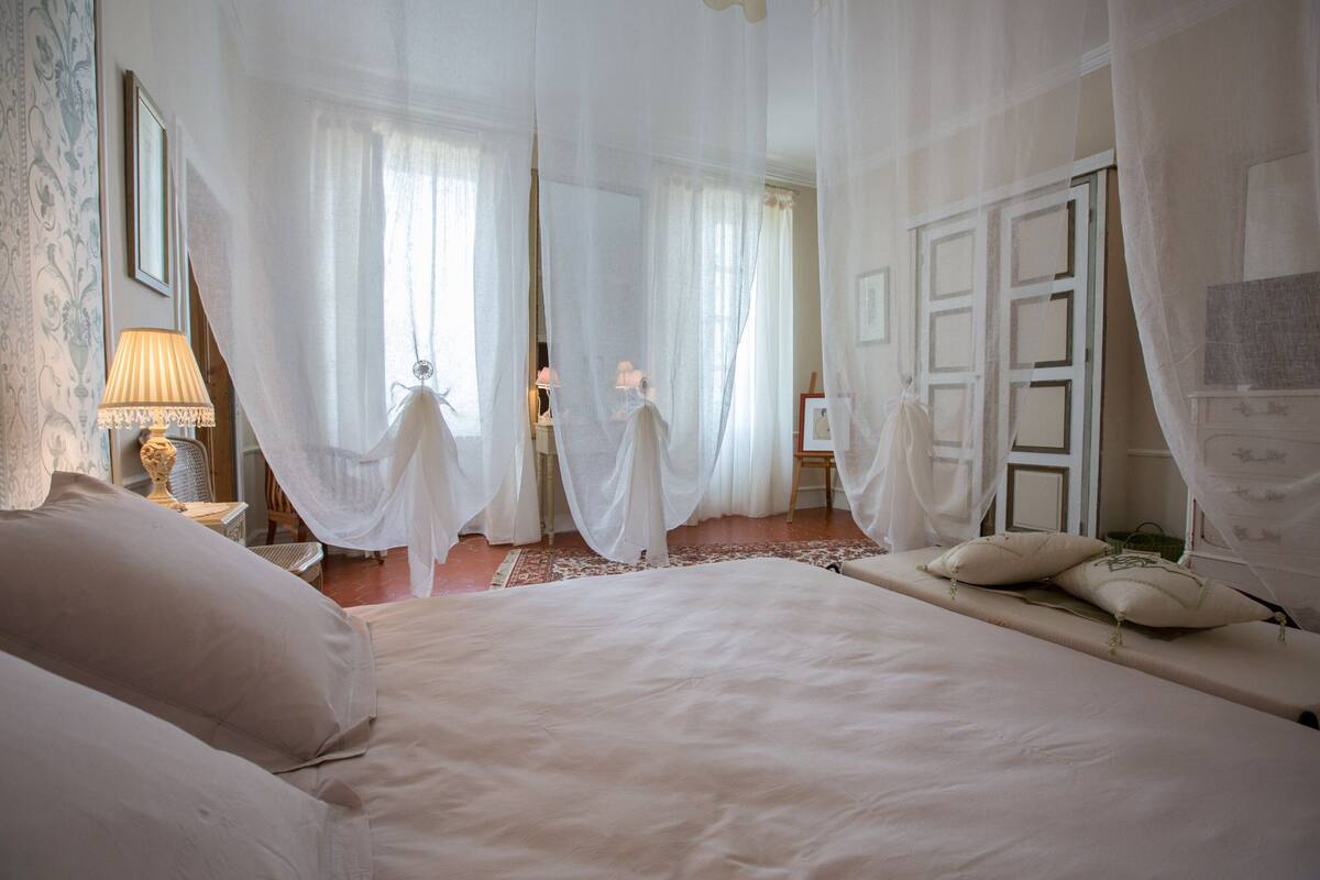 Un dormitorio con una cama grande, una mesita de noche con lámpara y una silla.