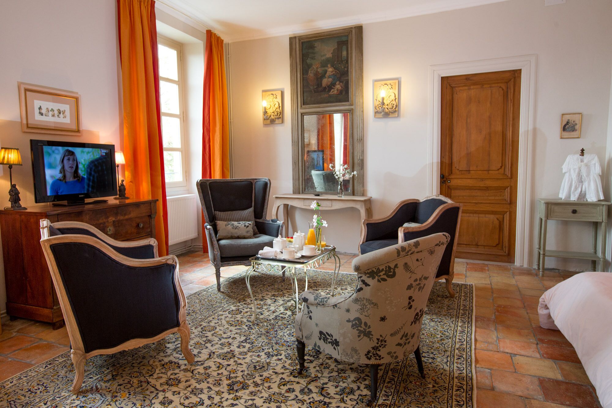 Una sala de estar bien amoblada con una televisión, dos sillones, un sofá, una mesa de centro y una mesa de comedor con una bandeja de alimentos para el desayuno.