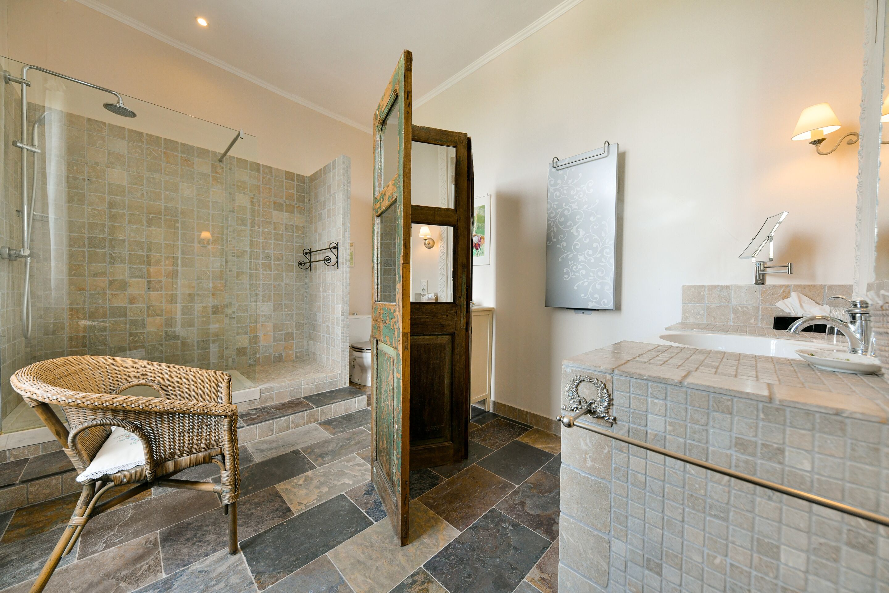 A bathroom with a shower, a sink, and a wicker chair.