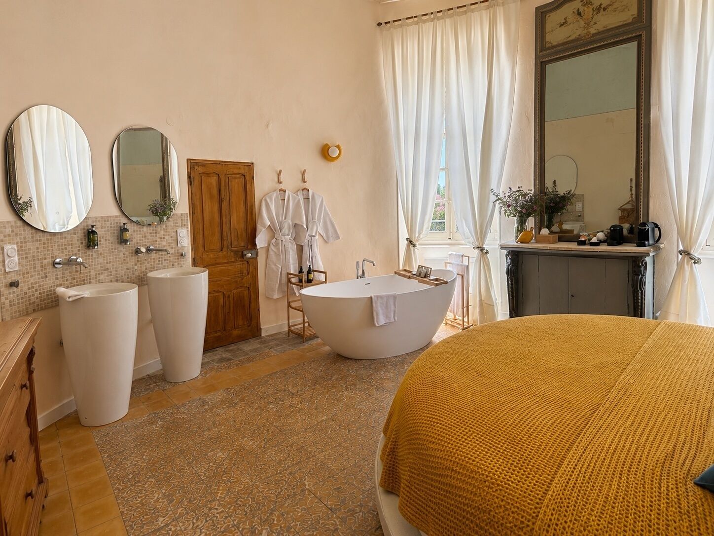 Une salle de bain avec une baignoire, deux lavabos, une porte en bois et un miroir.