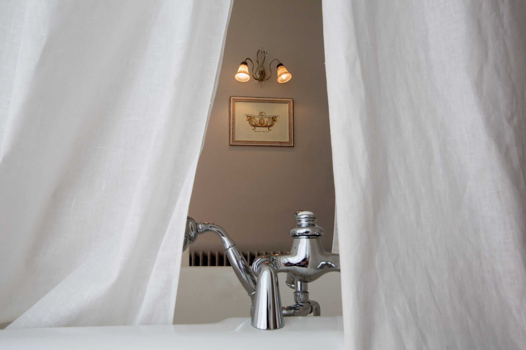 Un baño con un lavamanos blanco, un grifo cromado y un cuadro en la pared.