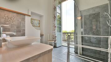 A modern bathroom with a large sink, shower, and a view of the outdoors.