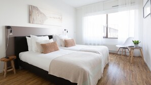 Una habitación de hotel moderna con dos camas, un ventanal grande, una silla y una mesita con una planta.