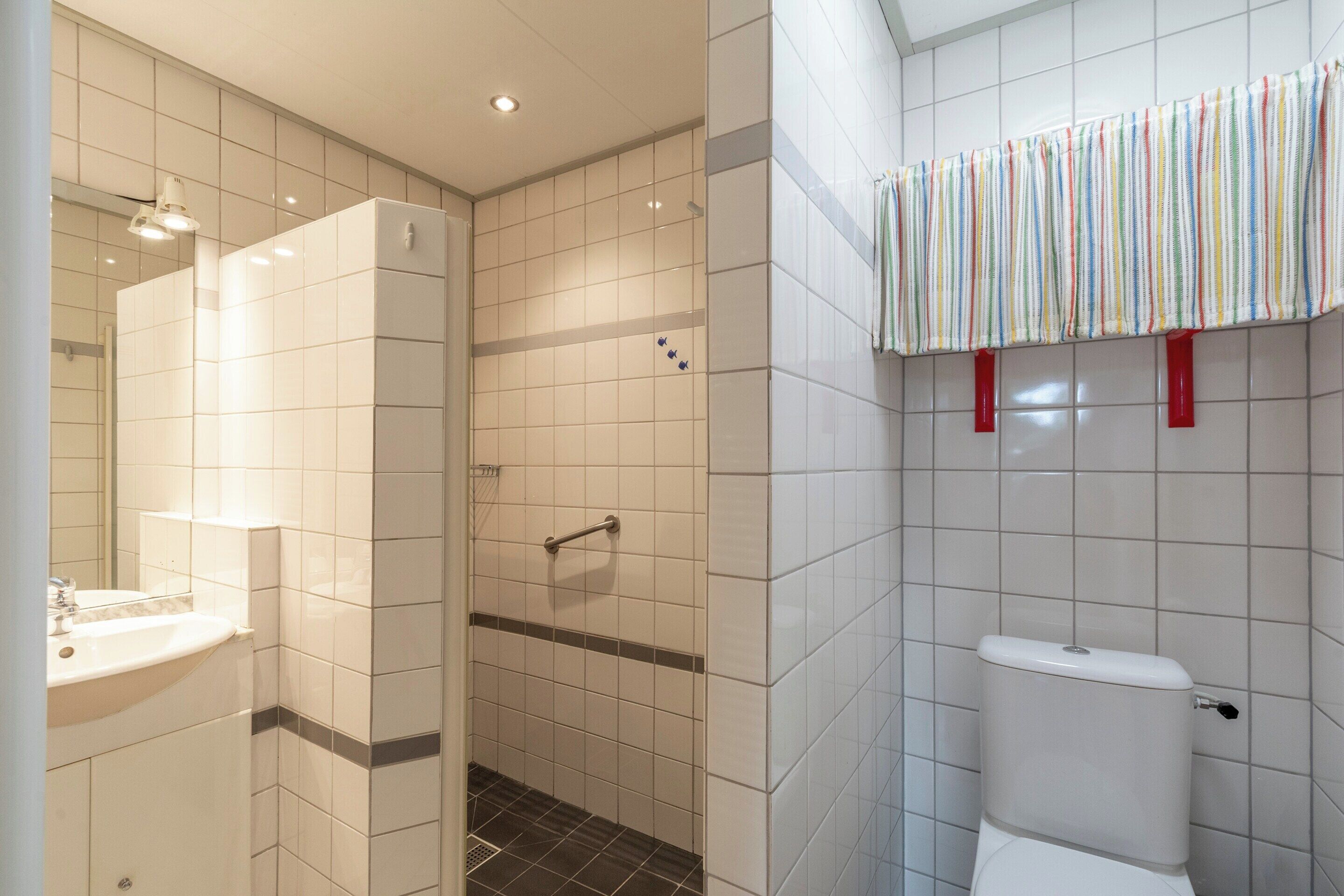 Un baño con lavamanos blanco, ducha e inodoro.