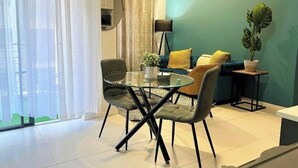 Een moderne woonkamer met een glazen eettafel, twee fauteuils, een bank en een potplant.