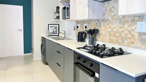 Een moderne keuken met een gasfornuis, een vaatwasser en een koffiezetapparaat.
