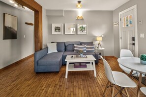 A modern living room with a sectional sofa, a coffee table, and a dining area with a round table and chairs.