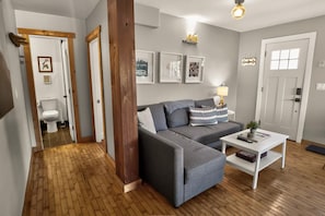 A modern living room with a grey sofa, a coffee table, and a wooden floor.