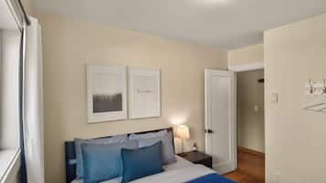 Una camera da letto con un letto, comodini, una lampada e due quadri appesi al muro.
