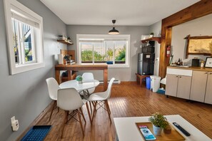 A compact kitchen with a dining area, wooden flooring, and a view through the window.
