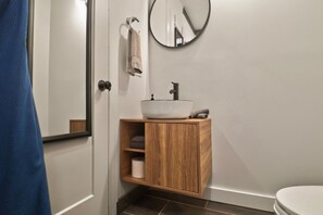 A bathroom with a wooden vanity, a round mirror, and a white sink.
