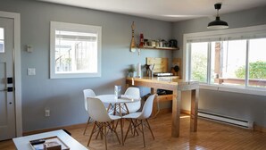 Una cucina moderna con un tavolo e sedie in legno, un forno integrato e una finestra vista verde.