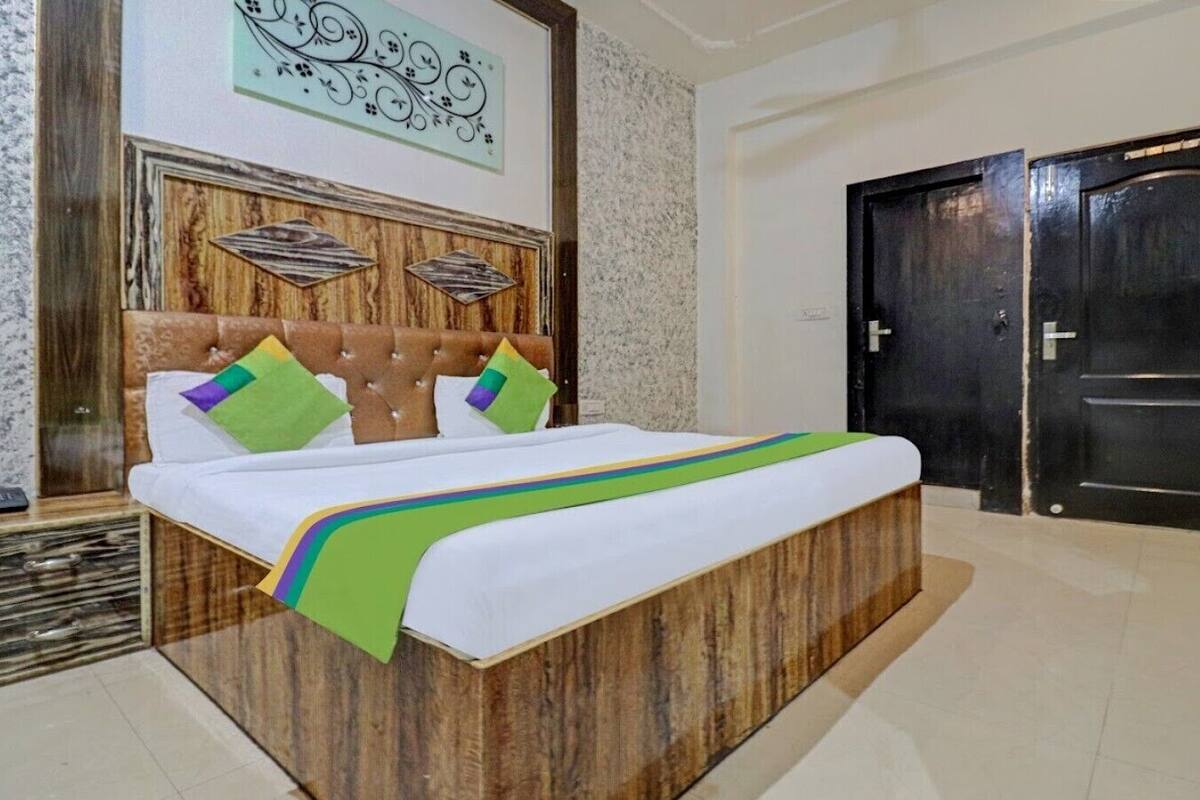 A bedroom with a wooden bed, a headboard with a decorative panel, and a large dark door.