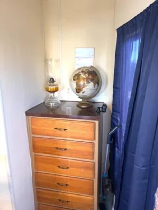 A wooden dresser with drawers, a globe, and a lamp on top.