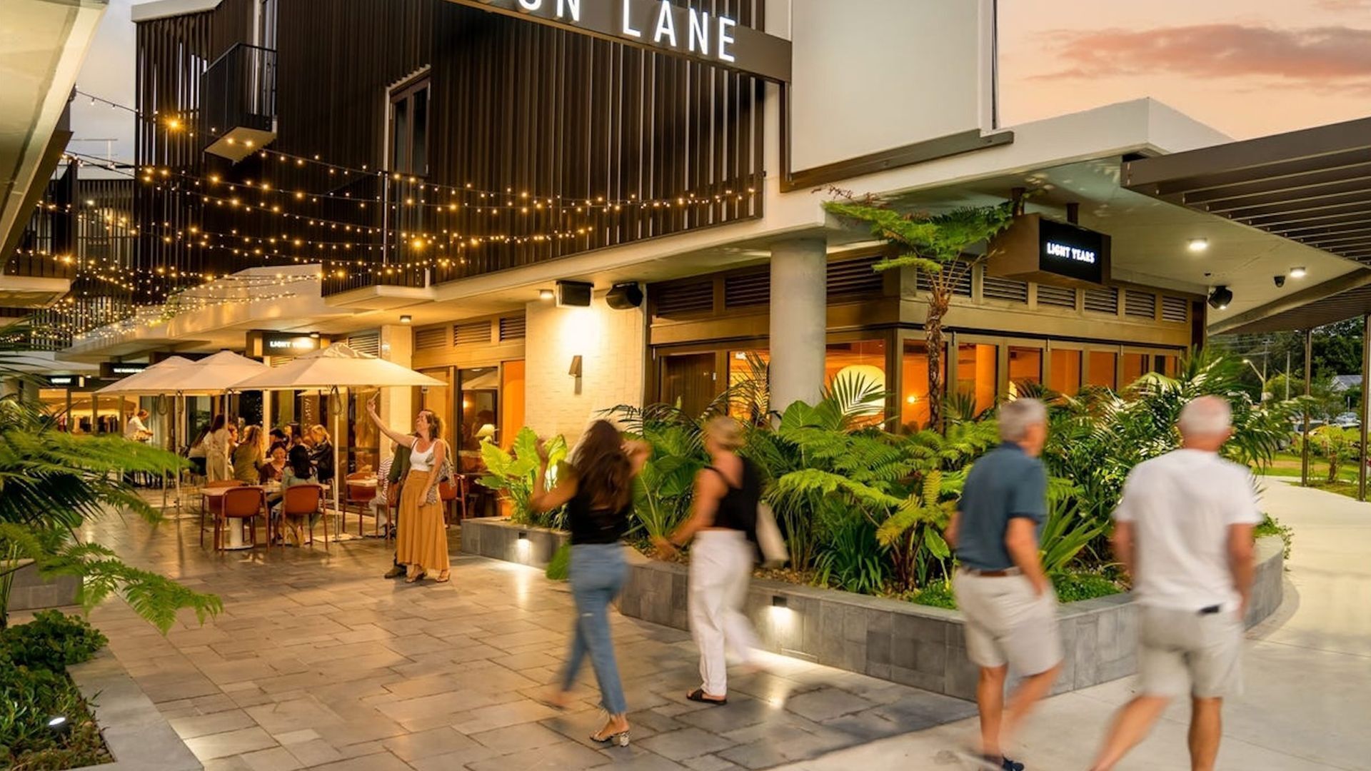 A modern building with a sign reading "LON LANE" and a restaurant area with outdoor seating.