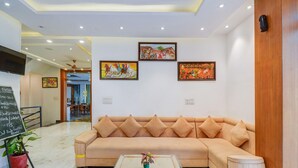 A modern lobby with a beige sofa, a coffee table, and artwork on the walls. - Comfort and Elegant Stays in Udaipur (Udaipur)