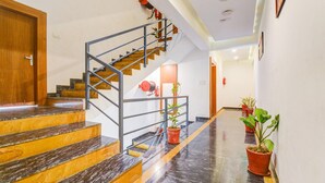 A staircase with a metal railing, wooden steps, and potted plants along the wall. - Comfort and Elegant Stays in Udaipur (Udaipur)
