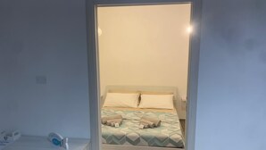A bedroom with a bed, pillows, and a bedside table with a lamp.