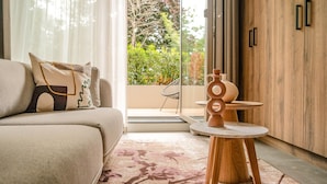 A modern living room with a sofa, a small round table, and a view of a garden through a glass door. - Sustainable Stay With Terrace (The Hague)