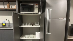 Kompakti keittiö, jossa on mikroaaltouuni, jääkaappi ja sisäänrakennettu kahvinkeitin.