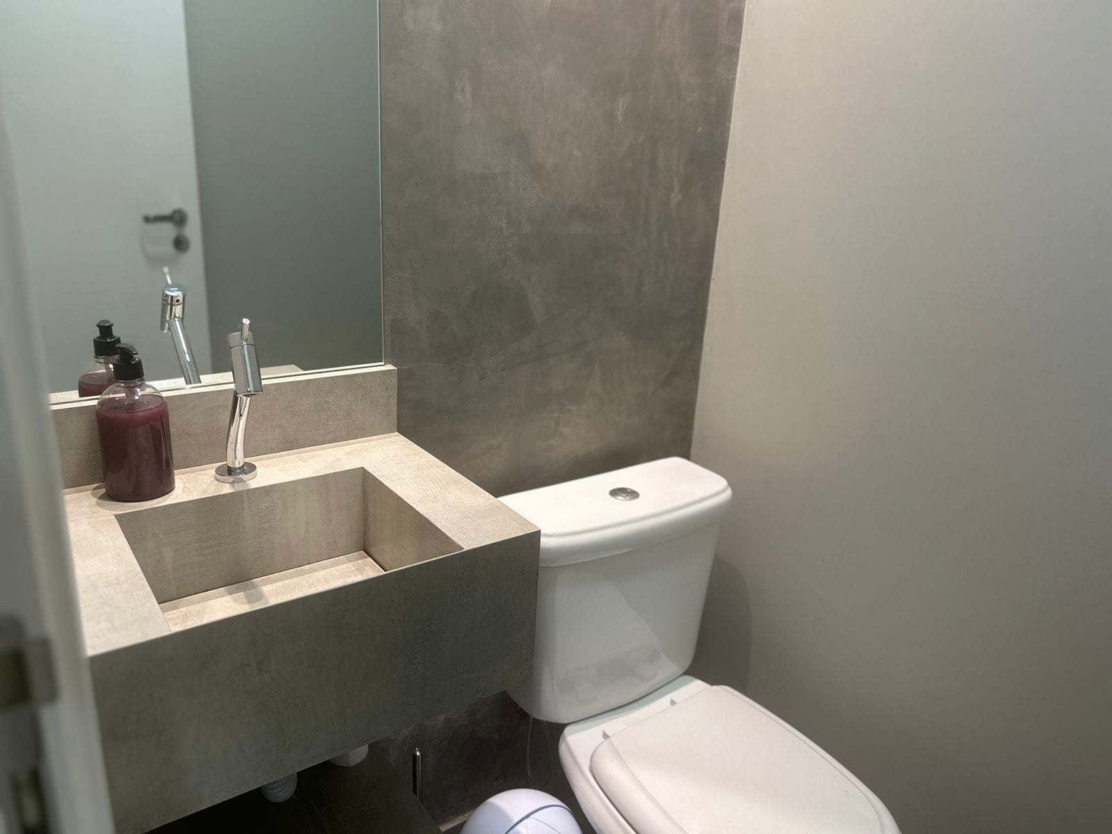 Un bany amb un lavabo beix, un vàter blanc i un mirall sobre el lavabo.