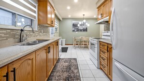 A modern kitchen with wooden cabinets, a granite countertop, a built-in oven, and a refrigerator. - Charming Home with Parking & Private Fenced Yard (Mississauga)
