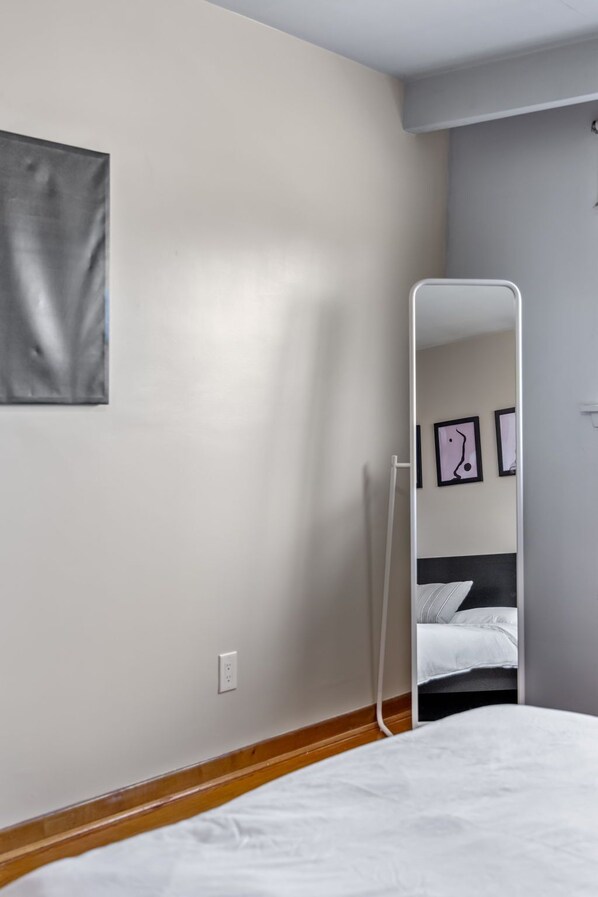 A bedroom with a bed, a mirror, and a wall-mounted picture frame.