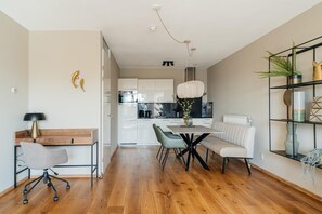 A modern kitchen with white cabinets, a dining table with chairs, and a pendant light. - Comfort Near Scheveningen (The Hague)