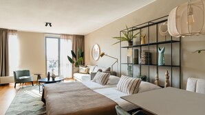 Ein modernes Hotelzimmer mit einem großen Bett, einem Esstisch, einer Couch und einem Bücherregal.
