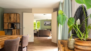 Una sala de estar moderna con una mesa de comedor de madera, sillas de cuero, un sofá y una planta grande.