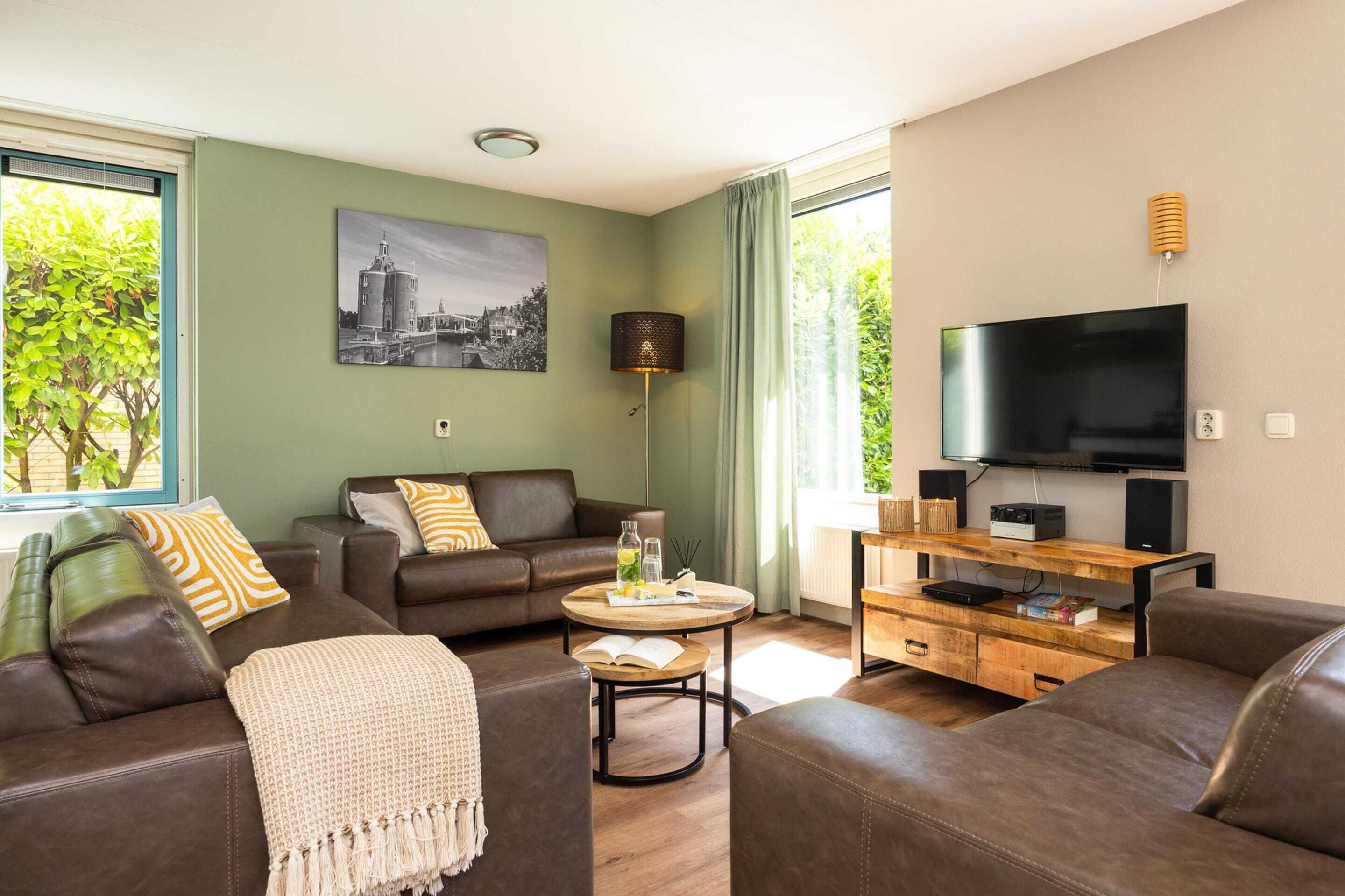 A modern living room with leather sofas, a coffee table, a TV, and a painting on the wall.