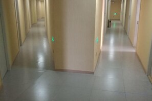 A long, narrow hallway with a tiled floor and walls, leading to a door at the end. - Changlai Hostel (Shanghai)