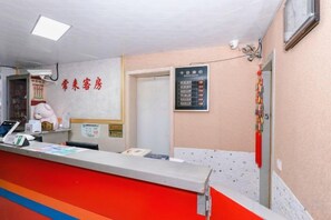 A reception area with a counter, a wall-mounted information board, and a door leading to another room. - Changlai Hostel (Shanghai)