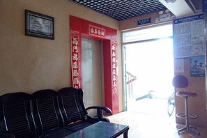 A waiting area with a reception desk, a red door with Chinese characters, and a poster on the wall. - Changlai Hostel (Shanghai)