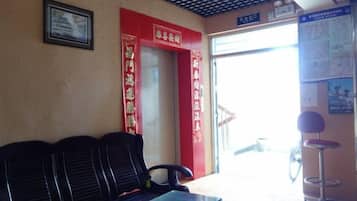 Uma área de espera com balcão de atendimento, um banco e uma porta que dá para o exterior.