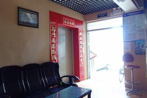 A waiting area with a reception desk, a bench, and a door leading outside. - Changlai Hostel (Shanghai)