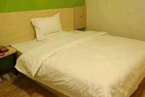 A single bed with a wooden headboard, a white pillow, and a white bedspread. - Changlai Hostel (Shanghai)