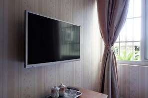 A television mounted on a wall, a window with curtains, and a tray with a teapot and cup. - Changlai Hostel (Shanghai)