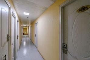 A hallway with doors on both sides, a light fixture on the ceiling, and a door with a number plate. - Changlai Hostel (Shanghai)