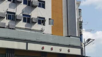 Um edifício com várias unidades de ar condicionado, uma faixa vertical amarela e uma placa com caracteres chineses.