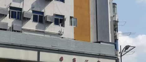 A building with multiple air conditioning units, a yellow vertical stripe, and a sign with Chinese characters.